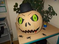 mit Gruselgesicht bemalter Kürbis und Hut